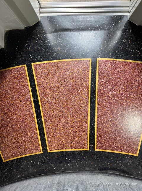 Trapèzes de granito rouge-brun cernés d'un filet de mosaïque jaune, sur fond noir